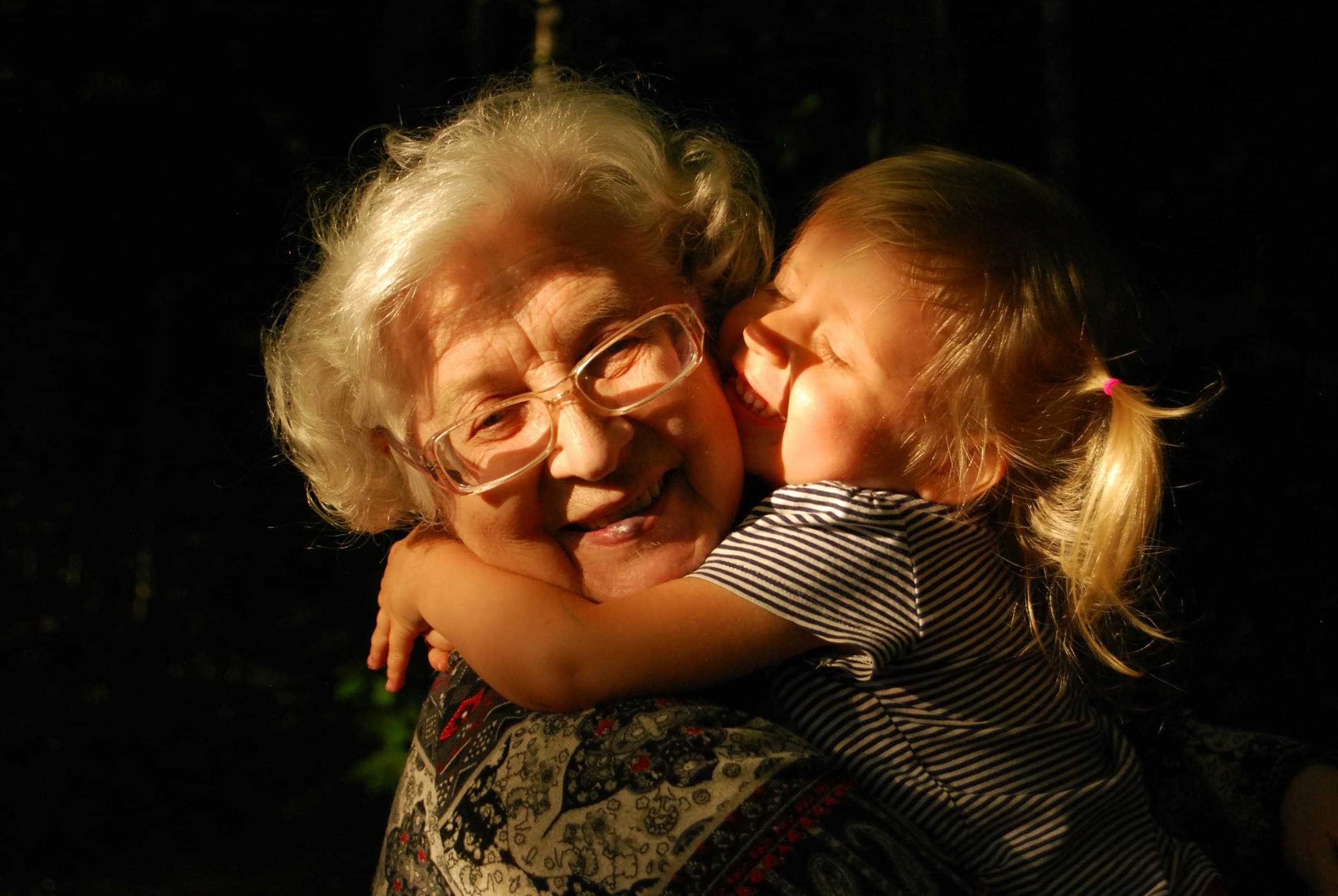 An older woman embracing a young child in a warm hug